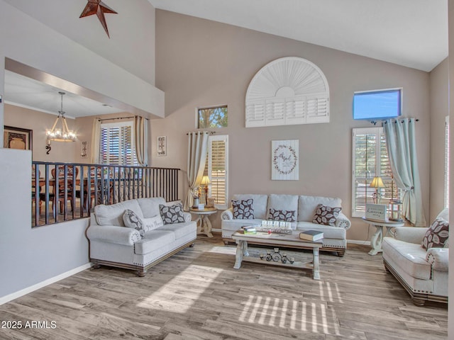 living room featuring a notable chandelier, wood-type flooring, and high vaulted ceiling