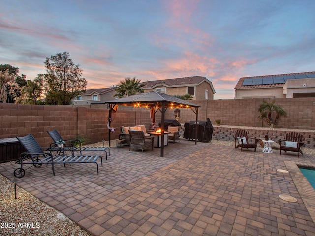 patio terrace at dusk featuring a fire pit and a gazebo