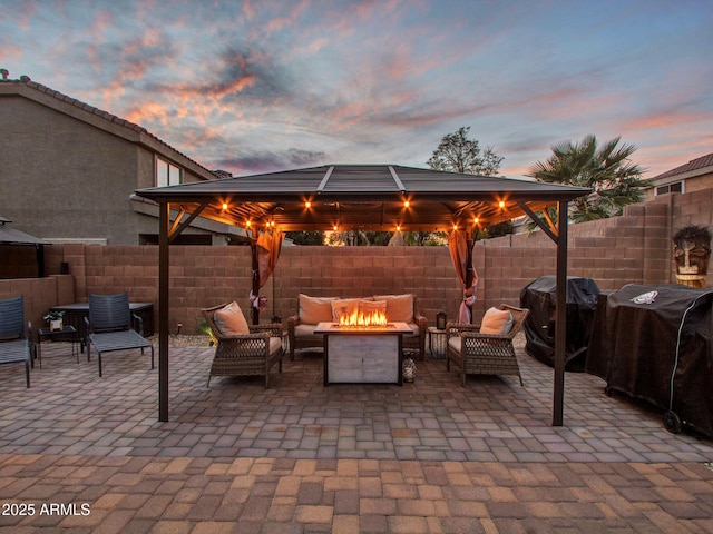 patio terrace at dusk featuring area for grilling, a gazebo, and an outdoor living space with a fire pit