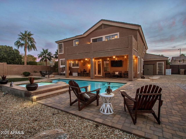 pool at dusk with a patio and an in ground hot tub