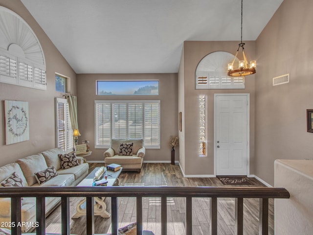 entryway featuring wood-type flooring, high vaulted ceiling, and an inviting chandelier