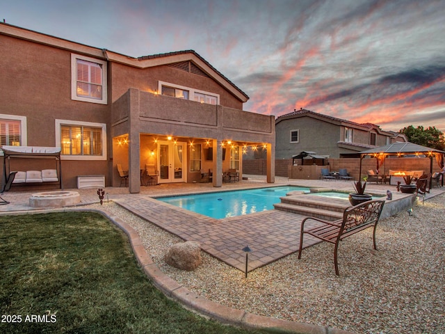 pool at dusk featuring a gazebo, an outdoor hot tub, and a patio