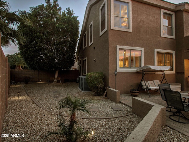 back house at dusk featuring a patio and central AC unit