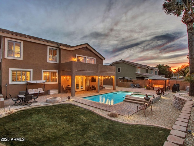 pool at dusk featuring an outdoor hot tub, a fire pit, a patio area, and a gazebo