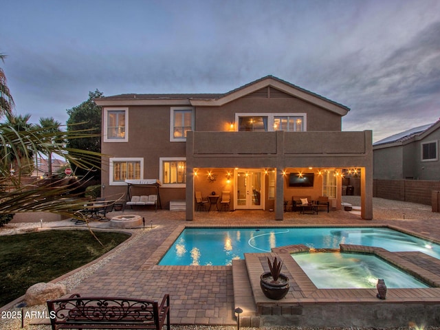 pool at dusk featuring an outdoor fire pit, a patio, and an in ground hot tub