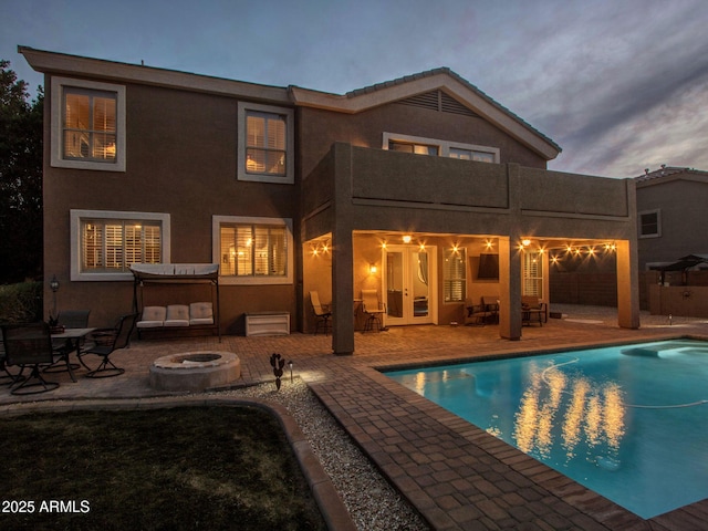 back of house with a pool with hot tub, a patio area, and an outdoor fire pit