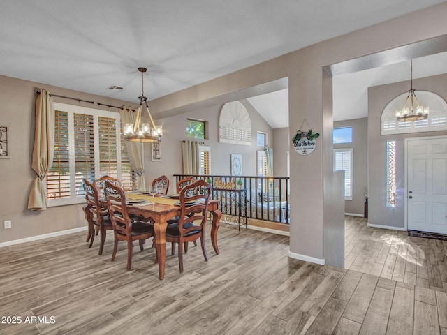 dining space with an inviting chandelier, lofted ceiling, and light hardwood / wood-style flooring