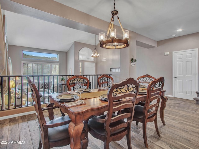 dining room featuring an inviting chandelier, vaulted ceiling, and hardwood / wood-style floors