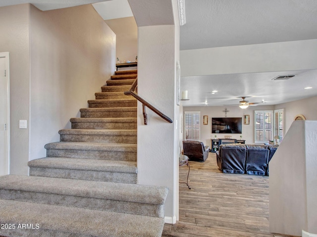 stairs featuring wood-type flooring and ceiling fan