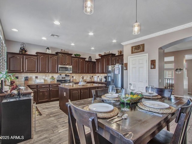 dining area with crown molding and light wood-type flooring