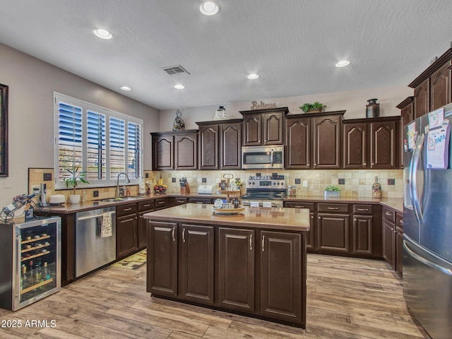 kitchen featuring stainless steel appliances, sink, wine cooler, and dark brown cabinetry