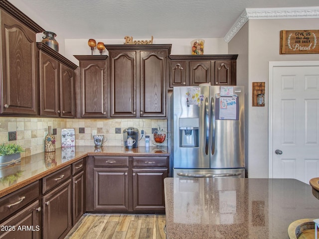 kitchen with dark brown cabinetry, stainless steel fridge with ice dispenser, and backsplash