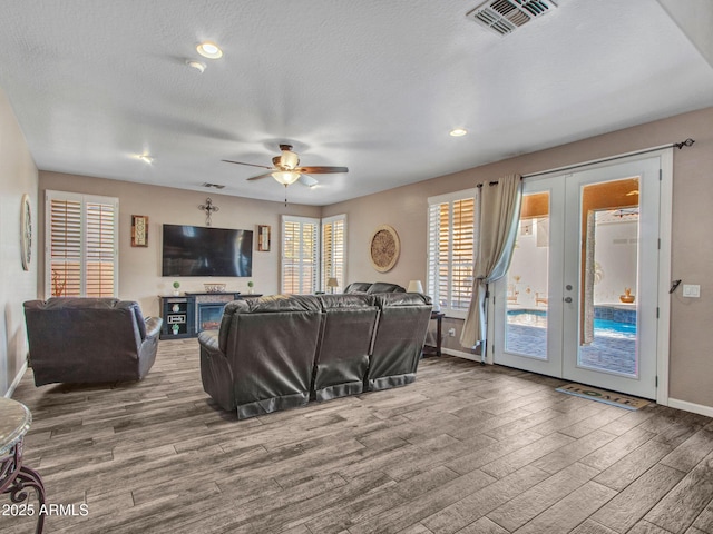 living room featuring wood-type flooring, ceiling fan, a textured ceiling, and french doors