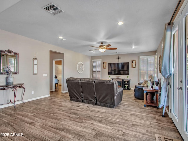 living room with ceiling fan, light hardwood / wood-style flooring, and a wealth of natural light