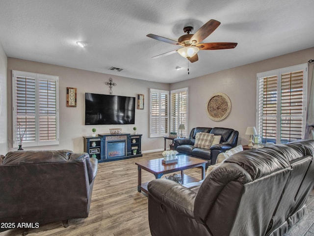 living room with ceiling fan, light hardwood / wood-style flooring, and a textured ceiling