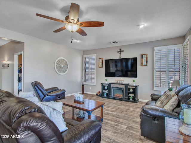 living room featuring ceiling fan, light hardwood / wood-style flooring, and a wealth of natural light