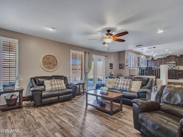 living room featuring ceiling fan, a textured ceiling, and light wood-type flooring