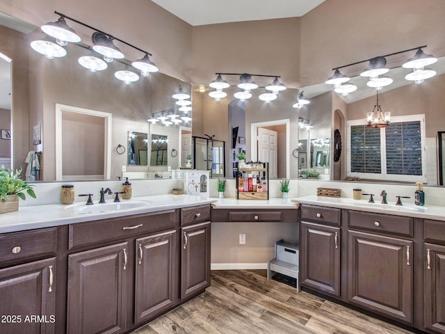 bathroom featuring hardwood / wood-style flooring, vanity, vaulted ceiling, and an inviting chandelier