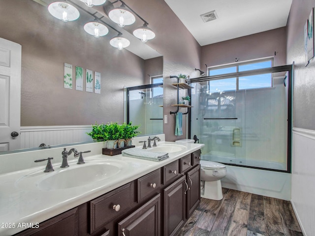 full bathroom with vanity, hardwood / wood-style floors, enclosed tub / shower combo, and toilet