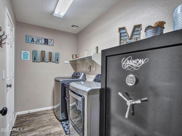 washroom with hardwood / wood-style flooring, washing machine and dryer, and a textured ceiling