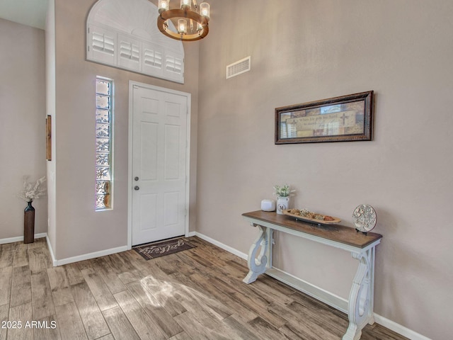 entryway with wood-type flooring and a chandelier