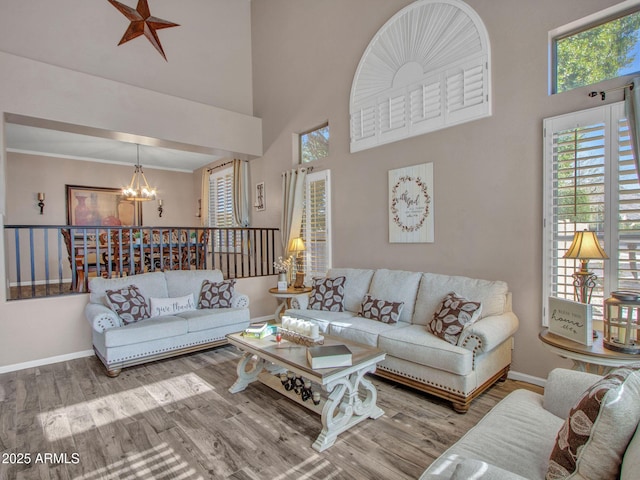 living room featuring a high ceiling, wood-type flooring, ornamental molding, and a chandelier