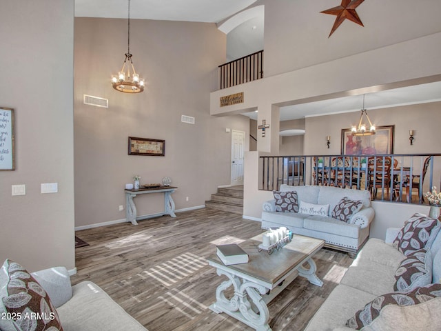 living room with hardwood / wood-style flooring, high vaulted ceiling, and a chandelier