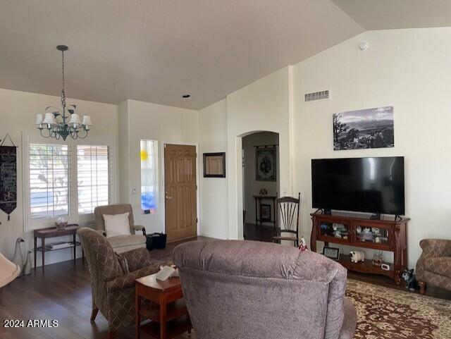 living room with a chandelier, lofted ceiling, and dark wood-type flooring