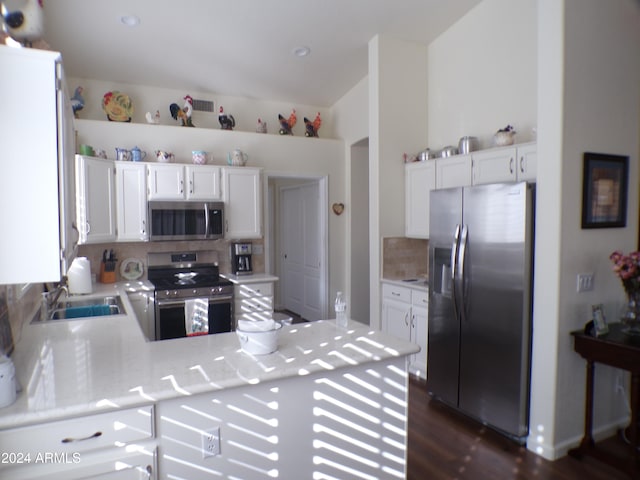 kitchen with kitchen peninsula, backsplash, stainless steel appliances, dark wood-type flooring, and white cabinets