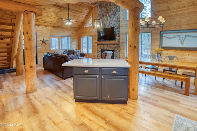 kitchen with gray cabinets, wood walls, a stone fireplace, wooden ceiling, and light wood-type flooring