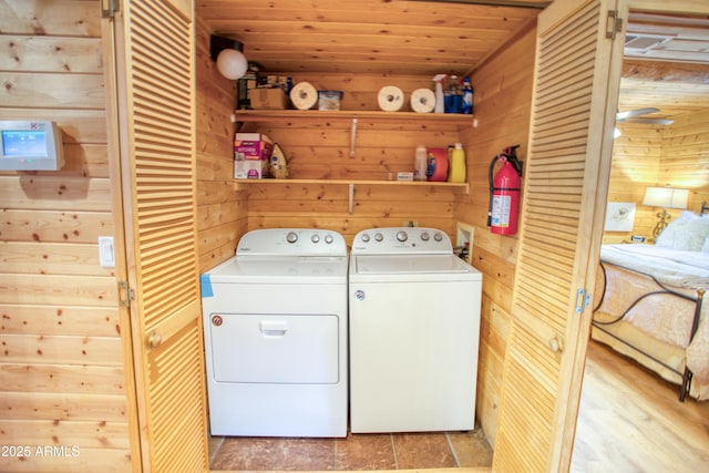 clothes washing area with wooden ceiling, washing machine and dryer, and wood walls