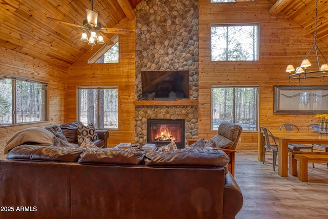 living room with wood ceiling, a stone fireplace, hardwood / wood-style flooring, and wood walls