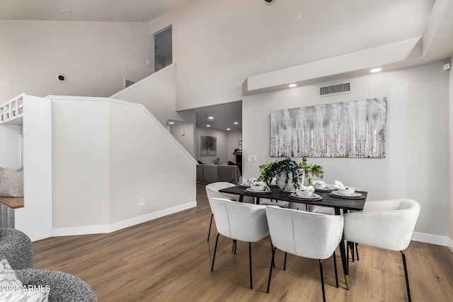 dining area with hardwood / wood-style floors and a high ceiling