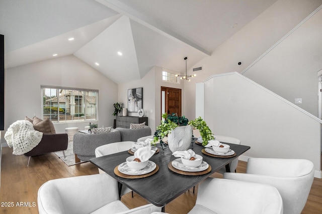 dining room with high vaulted ceiling, hardwood / wood-style floors, and an inviting chandelier