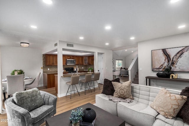 living room featuring sink and light hardwood / wood-style flooring