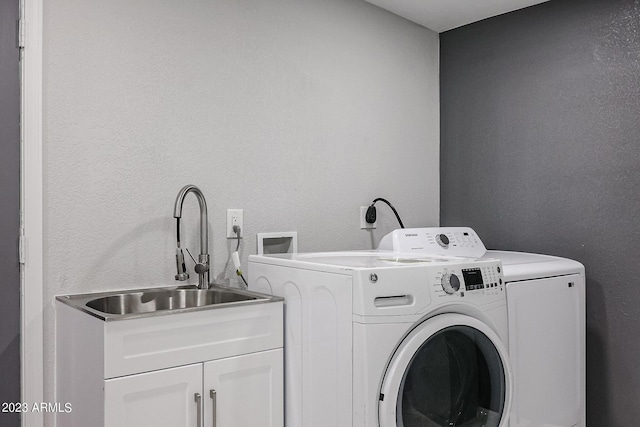 clothes washing area with cabinet space, washer and clothes dryer, and a sink
