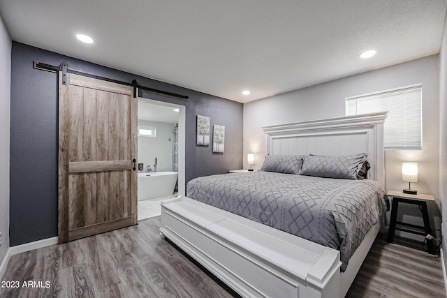 bedroom with baseboards, wood finished floors, recessed lighting, and a barn door