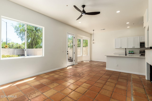 kitchen with appliances with stainless steel finishes, ceiling fan, dark tile patterned floors, and a wealth of natural light