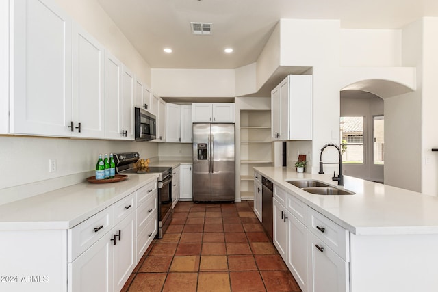 kitchen with white cabinetry, appliances with stainless steel finishes, sink, dark tile patterned flooring, and kitchen peninsula