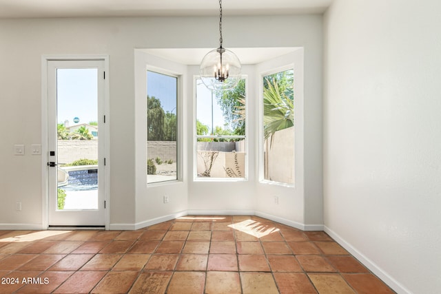 unfurnished dining area with tile patterned floors, a healthy amount of sunlight, and a chandelier