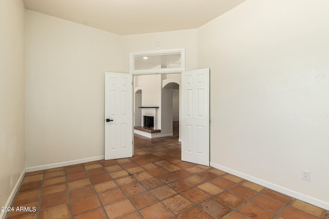 unfurnished room featuring dark tile patterned flooring and a multi sided fireplace