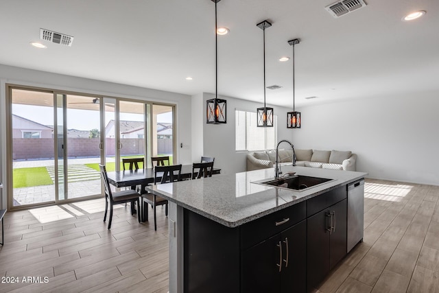 kitchen featuring light hardwood / wood-style flooring, stainless steel dishwasher, a kitchen island with sink, and sink