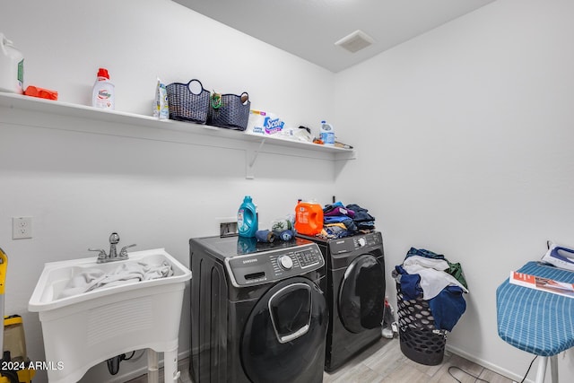 washroom with washer and clothes dryer, light hardwood / wood-style floors, and sink