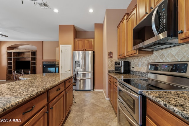 kitchen with visible vents, decorative backsplash, light tile patterned flooring, light stone counters, and appliances with stainless steel finishes
