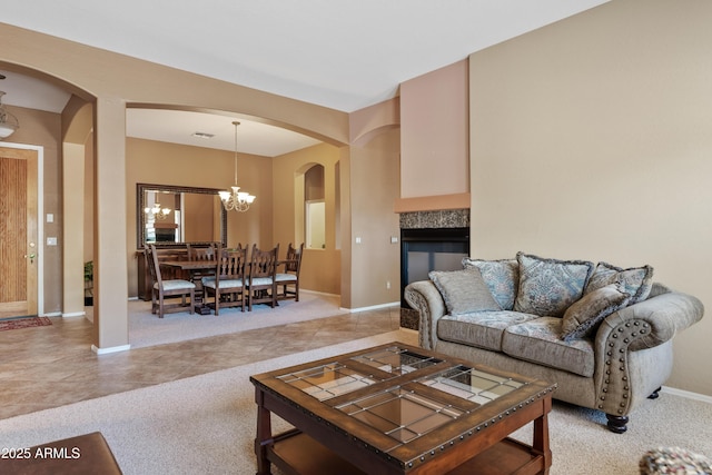 living area with visible vents, arched walkways, light tile patterned floors, baseboards, and a chandelier