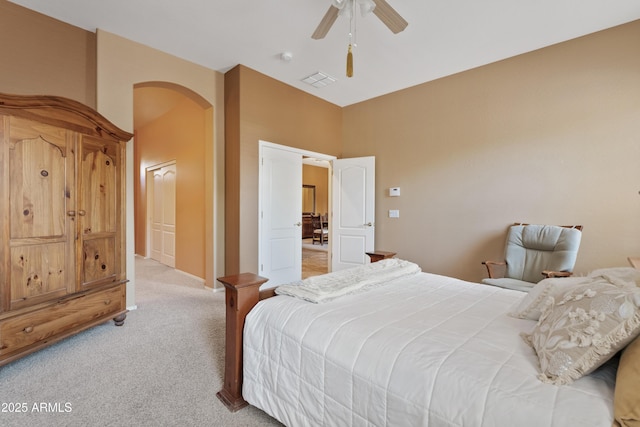 bedroom featuring a ceiling fan, visible vents, a towering ceiling, arched walkways, and light colored carpet