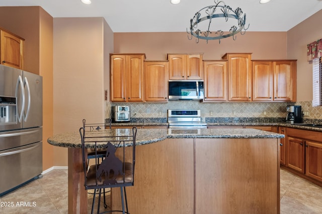 kitchen with dark stone counters, appliances with stainless steel finishes, and light tile patterned floors