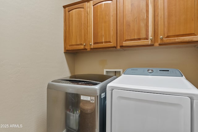 laundry room featuring a textured wall, cabinet space, and washing machine and clothes dryer