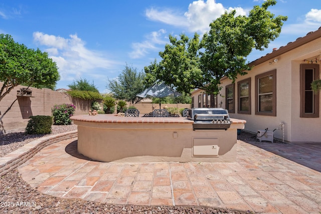 view of patio with a fenced backyard, exterior kitchen, and grilling area