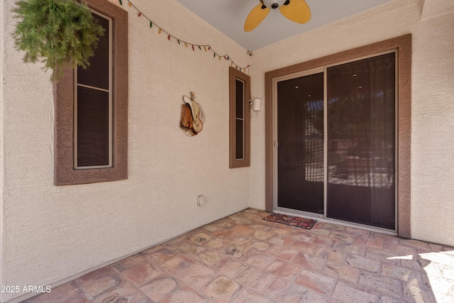 doorway to property with a ceiling fan, a patio, and stucco siding